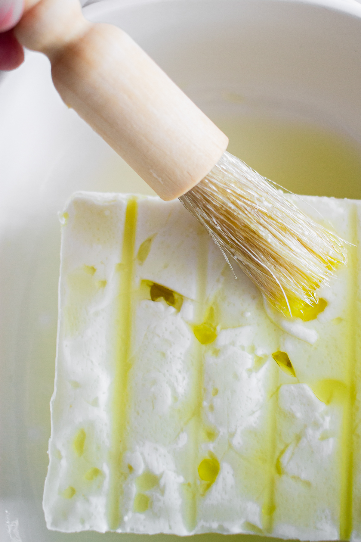 Brushing block of feta with olive oil.