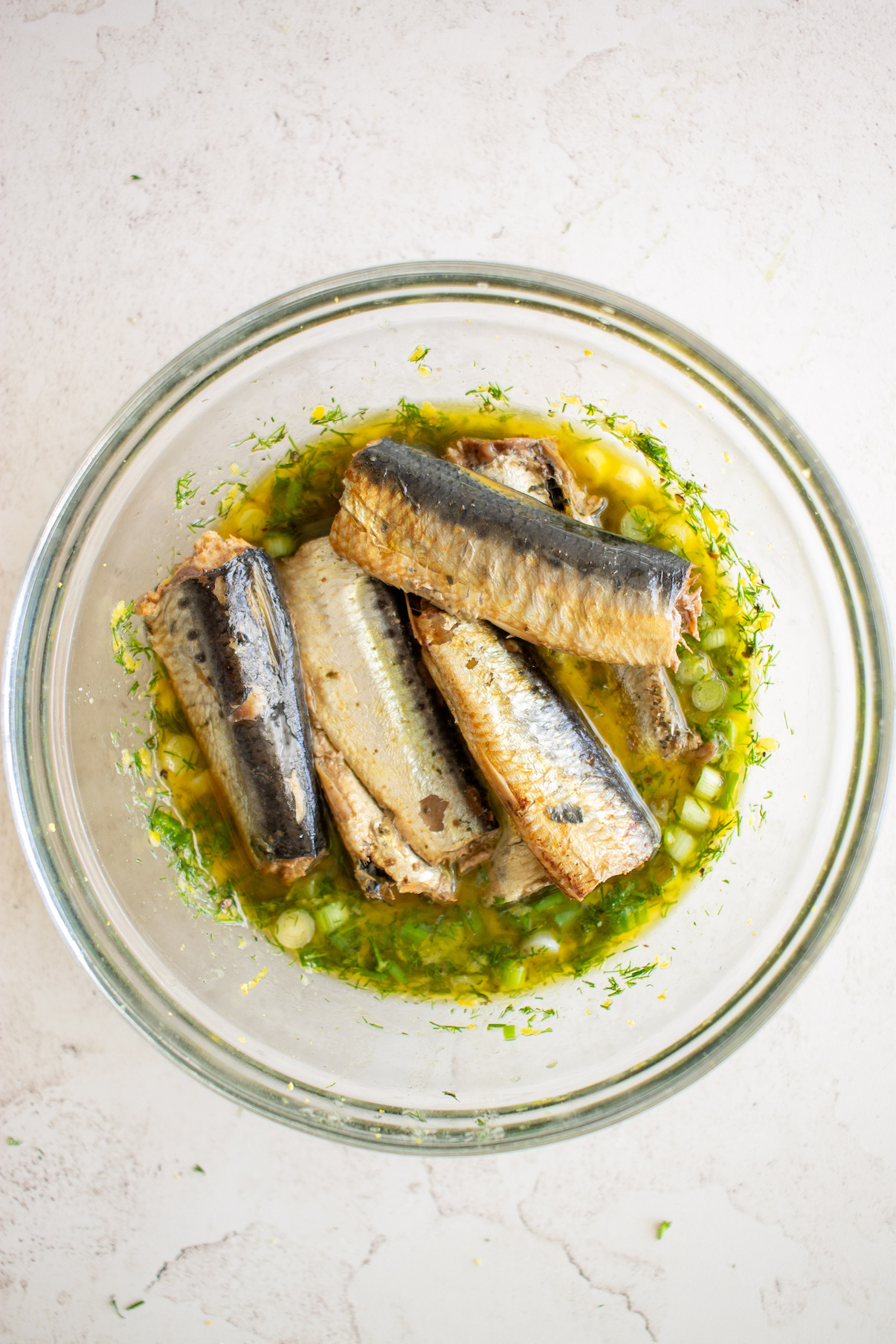 Sardine fillets in bowl of dressing.